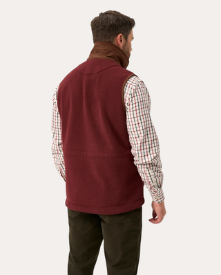 Hombre de espaldas vistiendo chaleco polar burdeos Alan Paine de Beviá sobre camisa de cuadros y pantalones oscuros