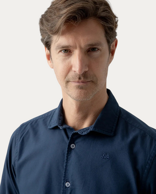 Hombre vistiendo camisa Beviá Oxford azul marino de algodón con cuello italiano y detalle de moto bordada