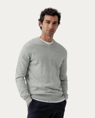 Modelo vistiendo jersey Beviá gris de algodón con cuello de pico y detalle de moto bordada en el pecho.